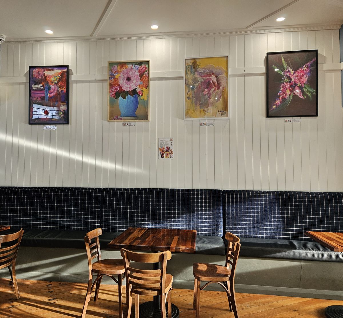 Four of Natalie Gardner's framed floral paintings hanging above the banquette seating at Beckman Deli Cafe, Glandore