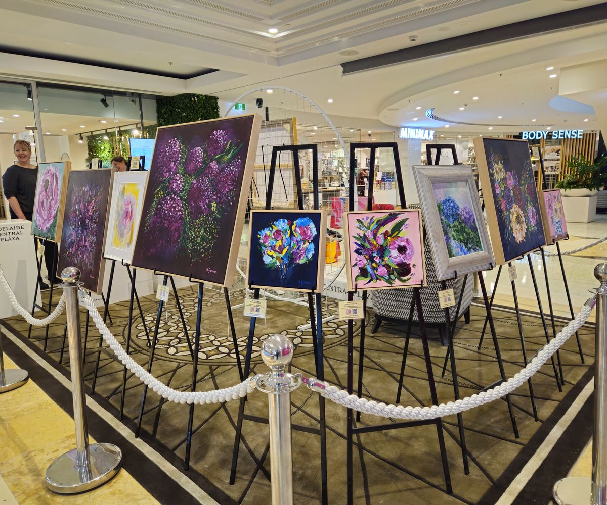 Rows of Natalie Gardner's floral paintings on easels at Adelaide Central Plaza