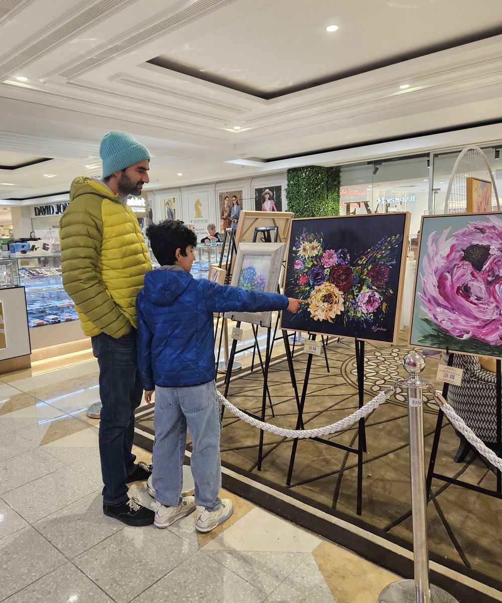 A father and son admiring a dark floral bouquet painting at the exhibition